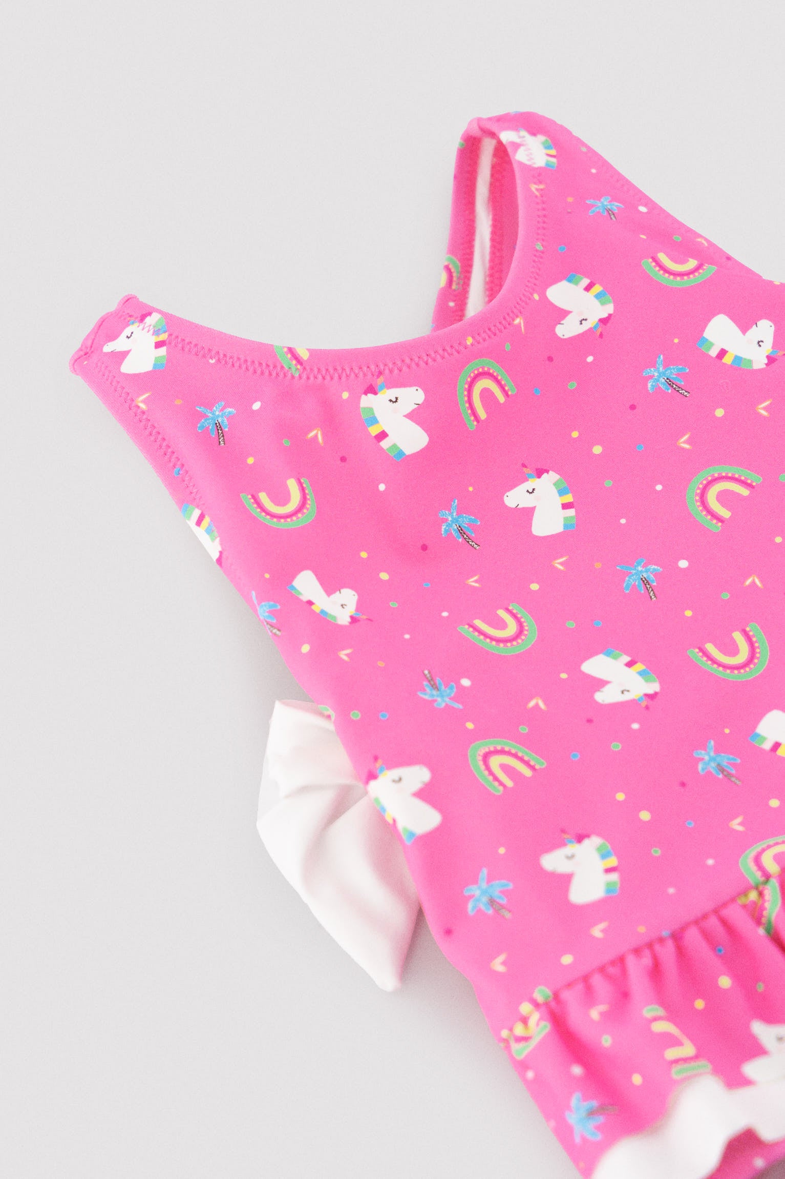 Baby girl swimsuit with ruffle and bow details, unicorn print